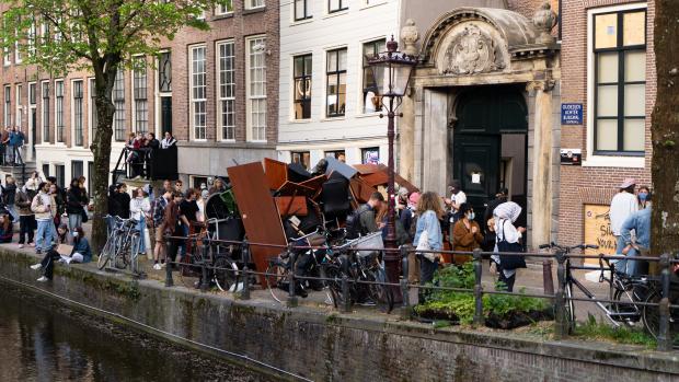 Politie grijpt vooralsnog niet inDe politie houdt de boel in de gaten, maar ziet vooralsnog geen reden tot ingrijpen. &lsquo;Het recht op demonstratie is een groot goed, maar als er eventueel strafbare feiten worden gepleegd, dan zal er eventueel worden ingegrepen&rsquo;, aldus een woordvoerder. Maar dat is volgens haar aan de driehoek: de burgemeester, OM en stadsbestuur. &nbsp;&nbsp;&lsquo;Voor nu is het wat ons betreft nog echt een demonstratie. We weten van de barricades&rsquo;, zegt de woordvoerder. &lsquo;Het protest begon op de UvA en trok toen door de stad. Wat we nu zien is dat de groepjes versplinterd zijn, er zitten wat mensen op de Dam, wat mensen rondom de Oudemanhuispoort. Van ingrijpen is er momenteel in elk geval geen sprake.&rsquo;
&nbsp;
Op zowel de Binnengasthuisstraat, de Grimburgwal als de Oudezijds Achterburgwal staat ME gestationeerd. Vooralsnog wordt niet ingegrepen en kunnen de demonstranten hun gang gaan met de bezetting en het opbouwen van de barricades. Ook wordt met graffiti een beveiligingscamera &ldquo;blind&rdquo; gespoten.